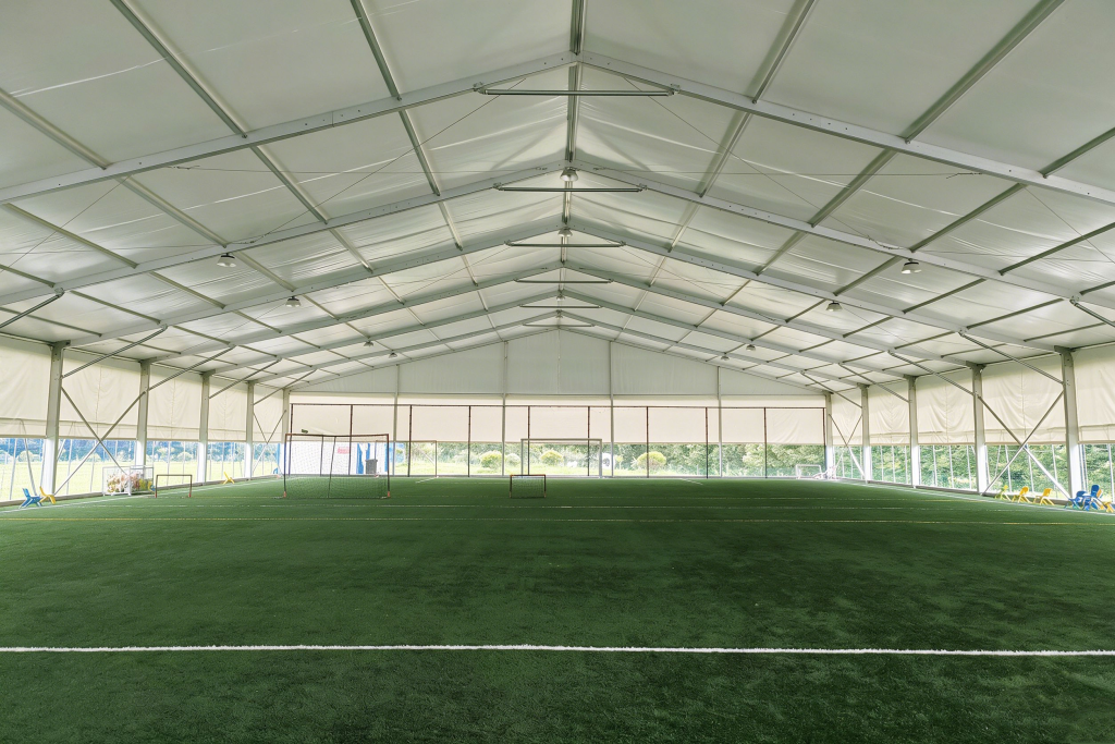 Clear Span Interior Design Without Support Pillars - Sports Tents Spacious interior of a clear-span sports tent by Toshimi Sports featuring artificial turf, demonstrating a pillar-free aluminum structure that maximizes playing area for commercial sports clubs.