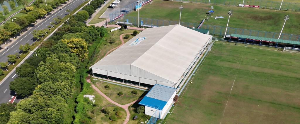 Toshimi Sports Aluminum Clear Span Sports Tent Installation Aerial view of a fully installed Toshimi Sports aluminum clear-span sports tent, showcasing a large-scale commercial sports facility integrated into a park environment.