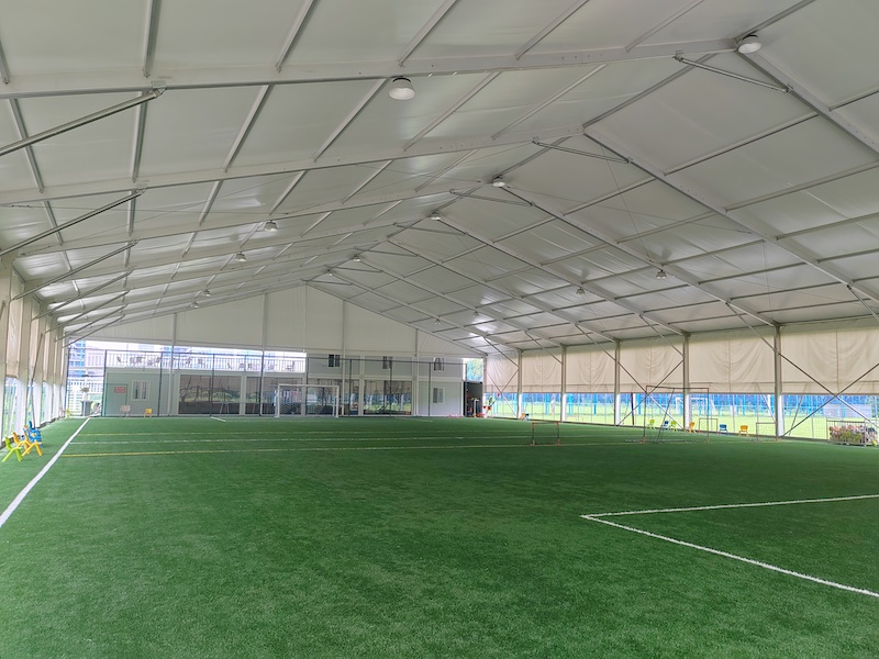 Spacious indoor soccer field enclosed by a Toshimi Sports clear-span tent, constructed purely with a heavy-duty aluminum alloy frame and a premium white tarpaulin cover.